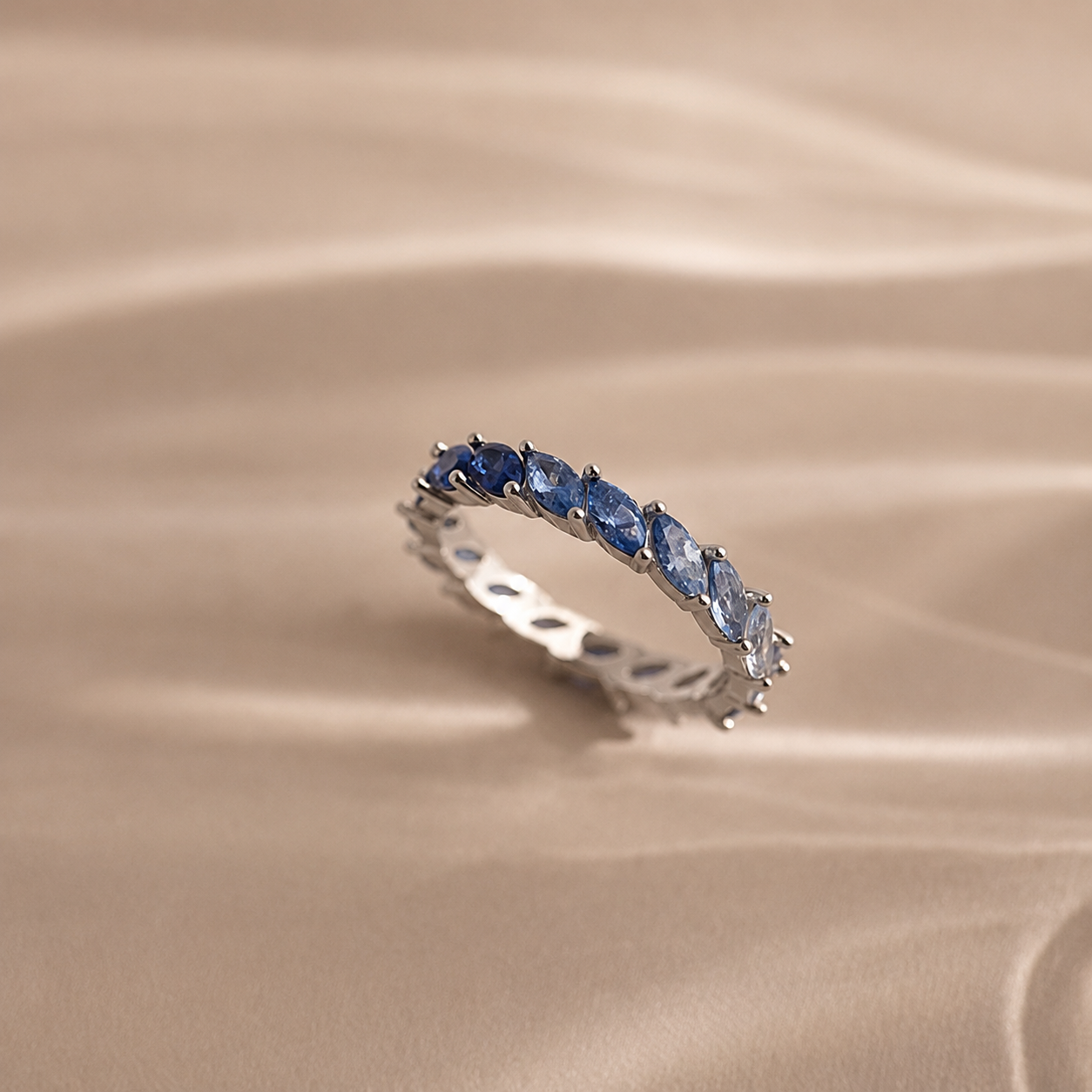 Silver ring with blue gemstones on a beige fabric background